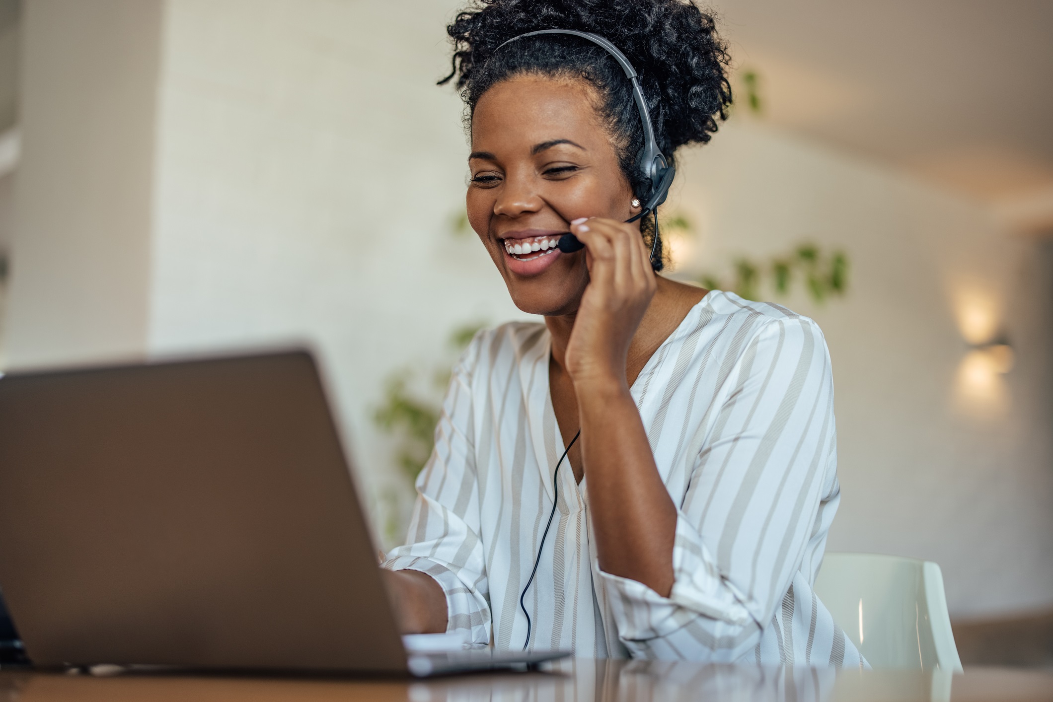 African-American customer support agent wearing a headset smiles as she assists a caller for customer service resolutions blog.