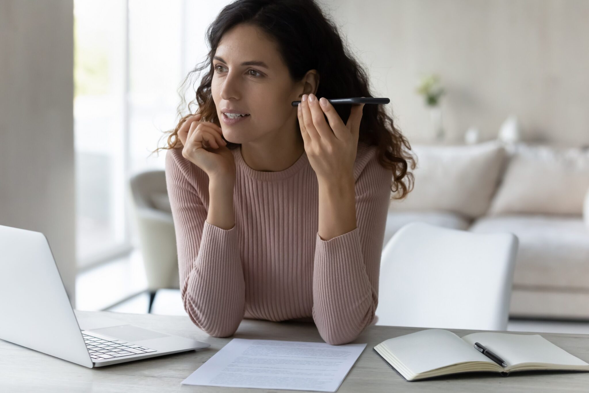 A young business woman listens intently to a voicemail on her smart phone for is voicemail a good way to make sales blog.