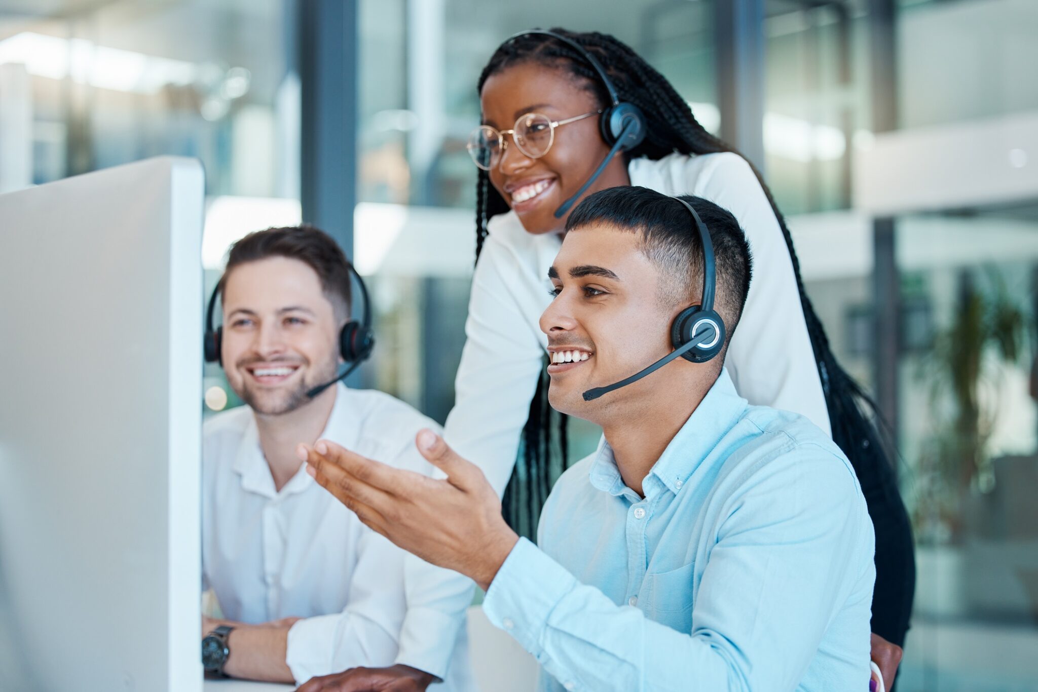 A young Black woman coaches a team of men at a call center for do people still use answering services blog.