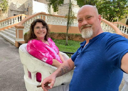 a man and a woman holding a baby in a pink and white toy car