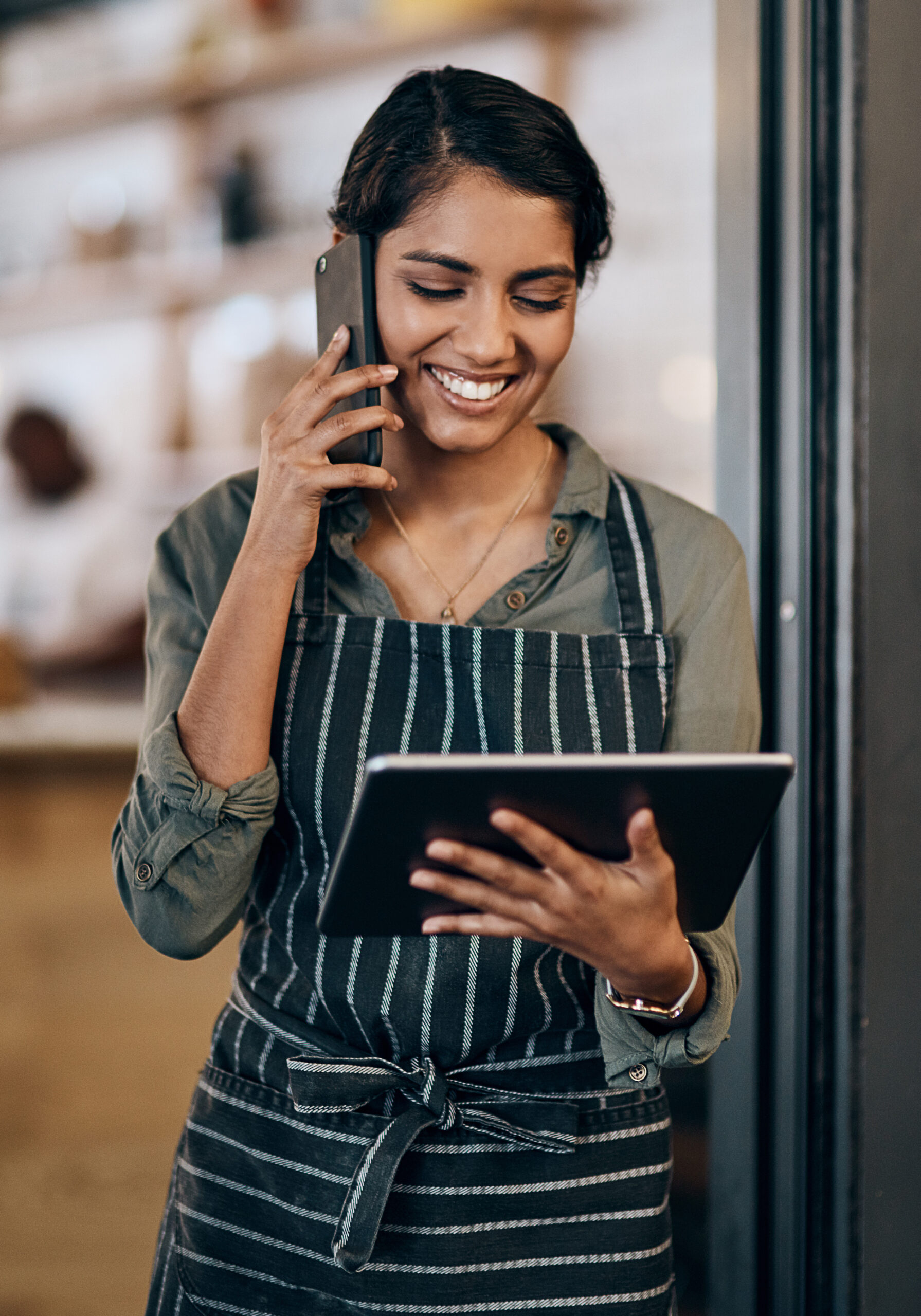 Shot of a young woman using a digital tablet and smartphone while working in cafe