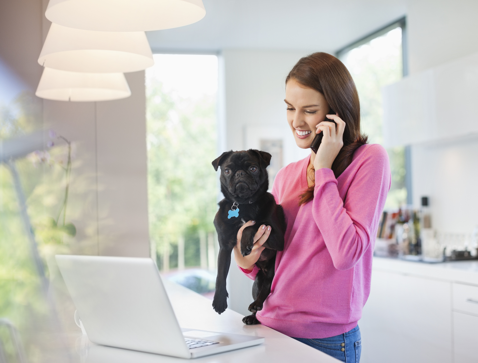 Woman on cell phone holding black pug for Focus Answering Service