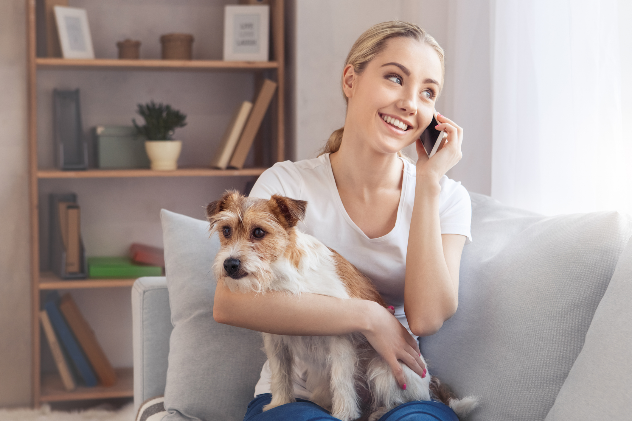 Woman on phone while holding dog on couch for Focus Answering Service